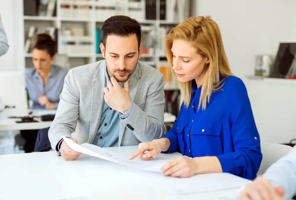 Two professionals reviewing documents together during a collaborative office meeting in a modern workplace setting
